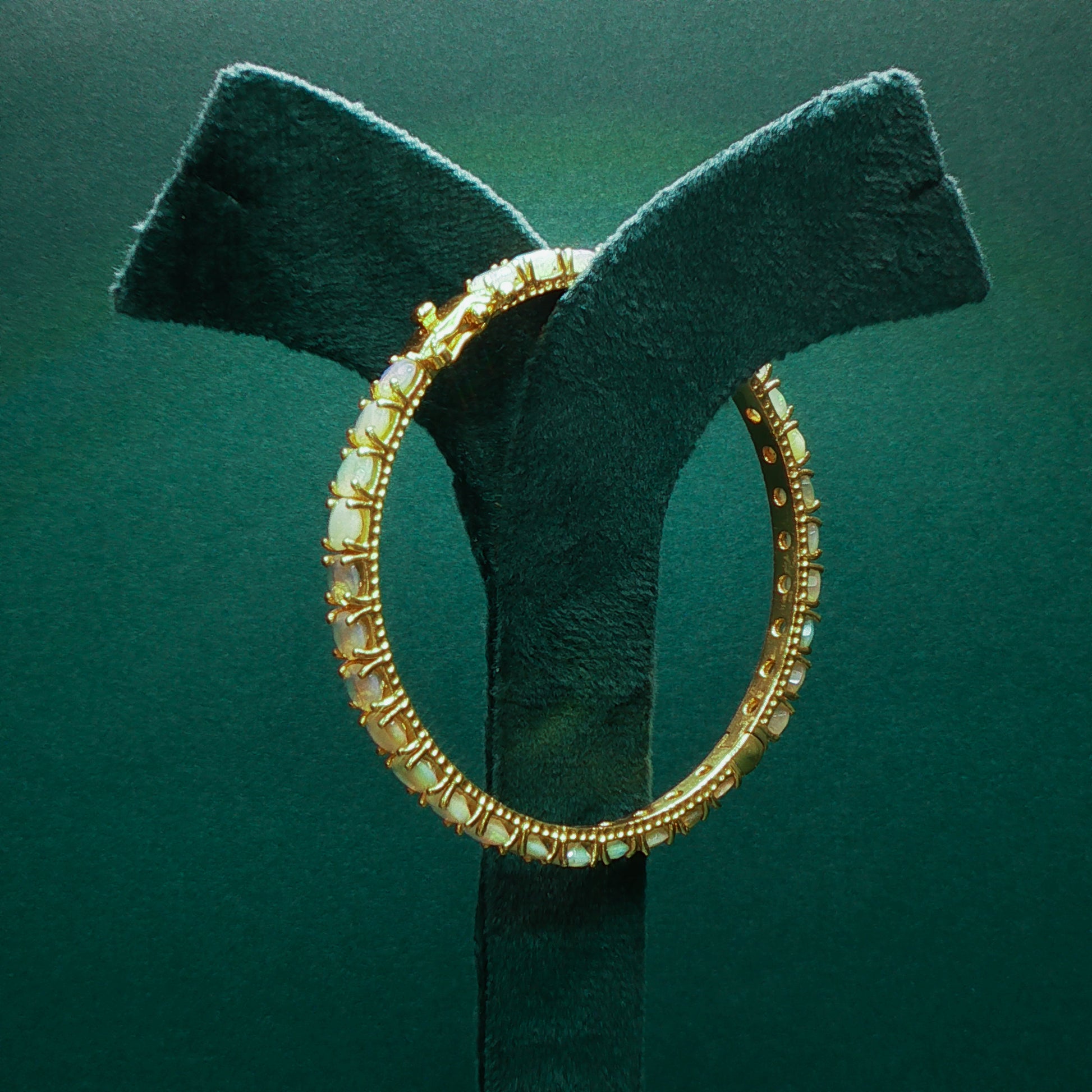 silver hoop earring on a green velvet stand against a green background

