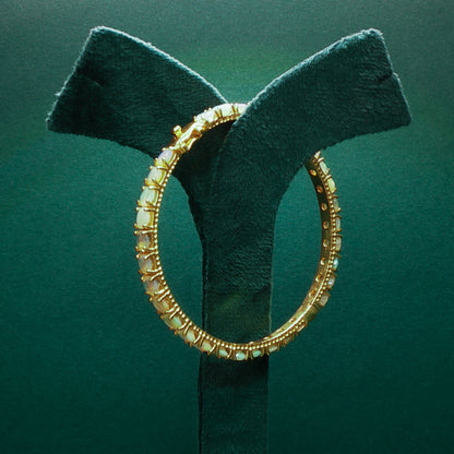 silver hoop earring on a green velvet stand against a green background

