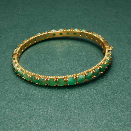 silver bracelet with green gemstones on a green background

