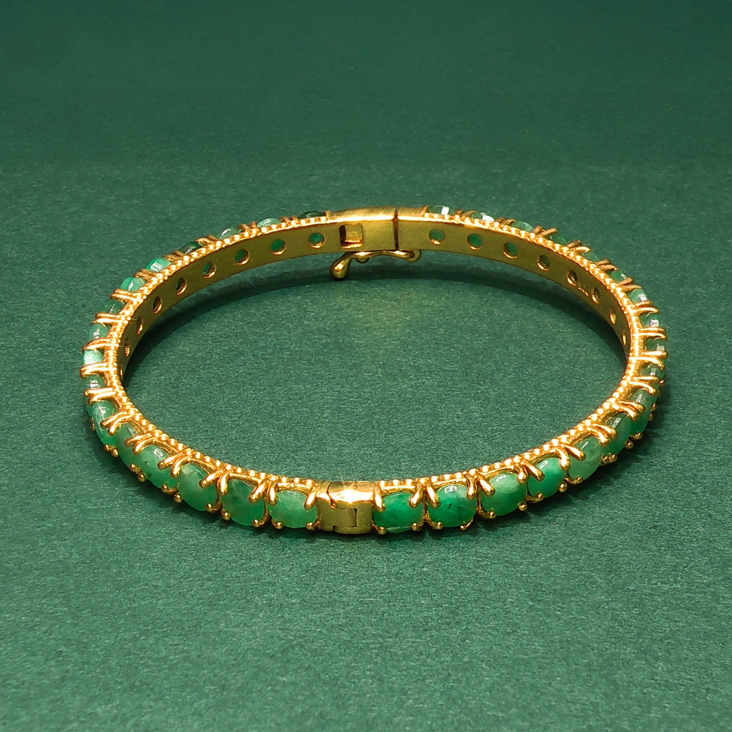 silver bracelet with green gemstones on a green background

