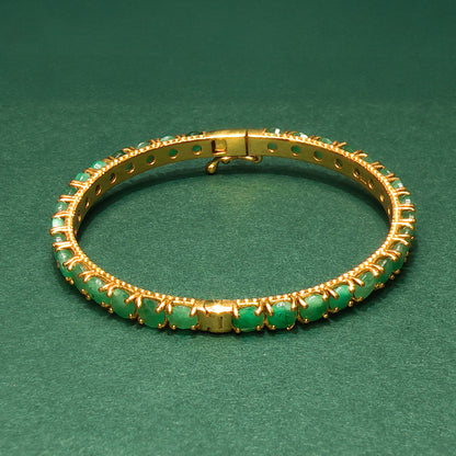 silver bracelet with green gemstones on a green background

