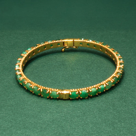 silver bracelet with green gemstones on a green background

