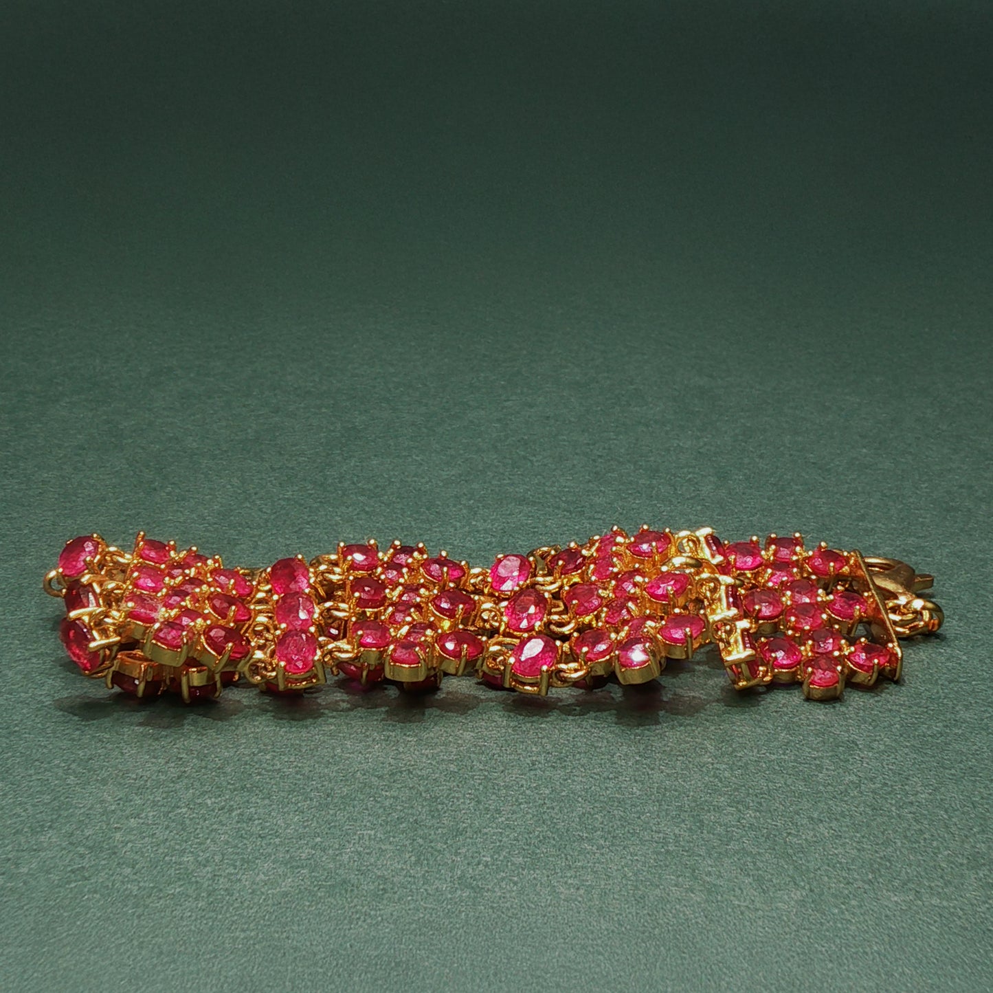 silver bracelet with pink gemstones on a green background

