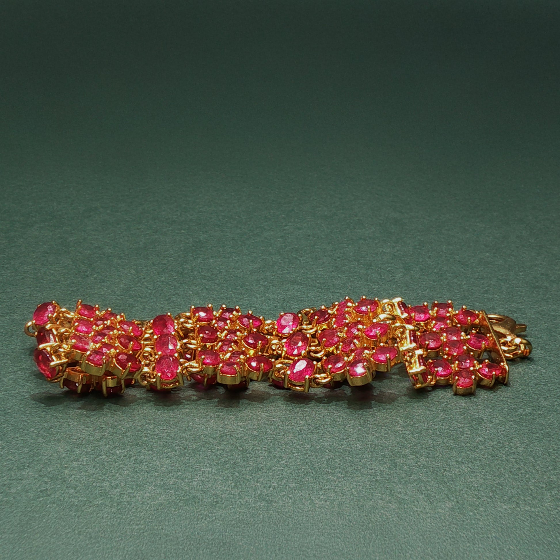 silver bracelet with pink gemstones on a green background

